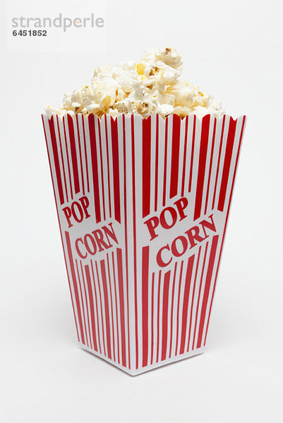 Studioaufnahme einer rot gestreiften Schachtel Popcorn mit aufgedrucktem Popcorn