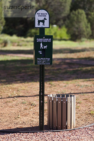 Schild und Behälter für Haustierabfälle in einem Park