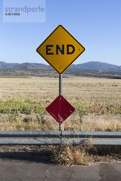 Ein END-Schild und Bergketten dahinter