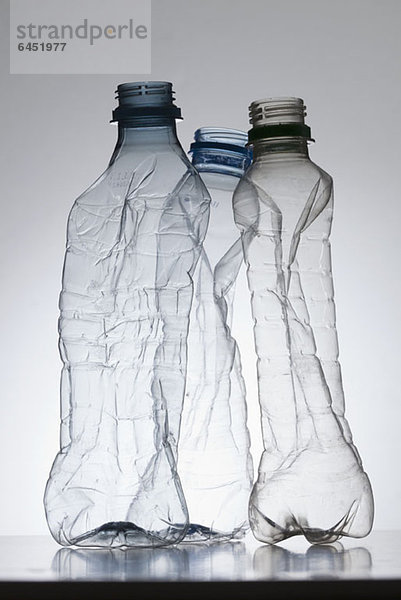 Drei leere  teilweise zerkleinerte Kunststoff-Wasserflaschen