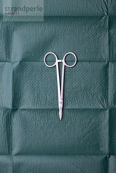 Eine chirurgische Schere auf einem chirurgischen Tuch