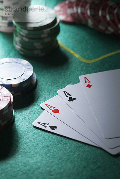 Eine Hand von Karten mit vier Assen  Spielchips im Hintergrund