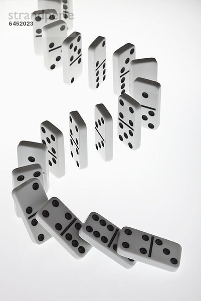 Dominosteine in einer Reihe  die in einer Kettenreaktion umfallen.