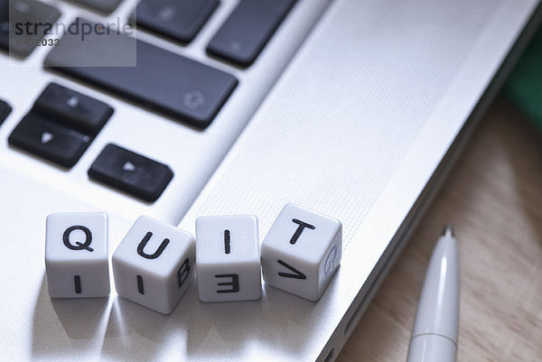 Buchstabenwürfel auf einem Laptop mit der Schreibweise QUIT