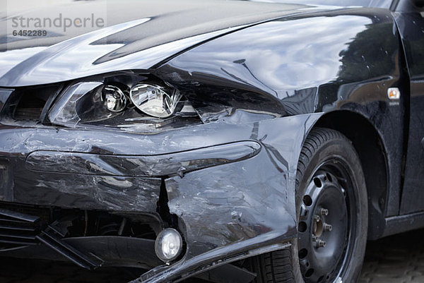 Beschädigtes Auto mit verzerrter Spiegelung der Stadt