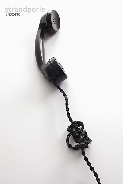Eine altmodische Telefonschnur  die sich in einem Knoten verheddert hat.
