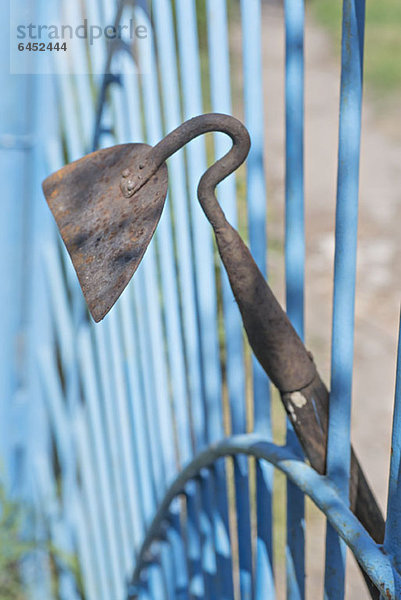 Eine an ein Tor gelehnte Gartenhacke