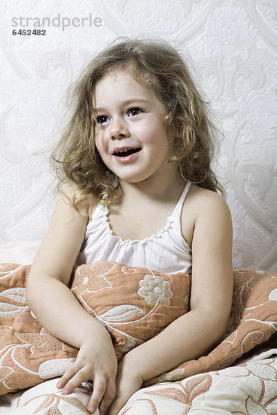 Ein junges Mädchen sitzt unter einer Decke.