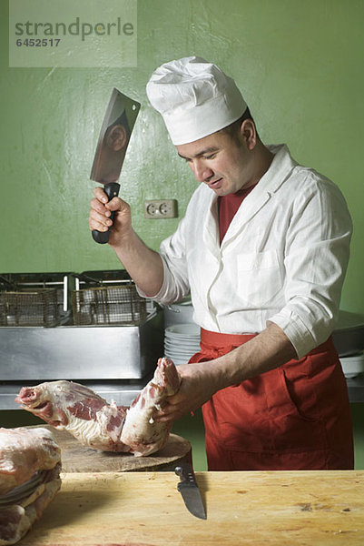 Ein Metzger hackt Fleisch mit einem Hackbeil