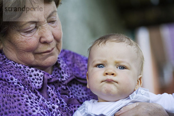 Eine ältere Frau hält ein Baby.