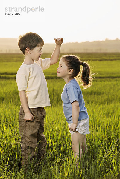 Ein Junge und ein Mädchen in einem Feld vergleichen Höhen