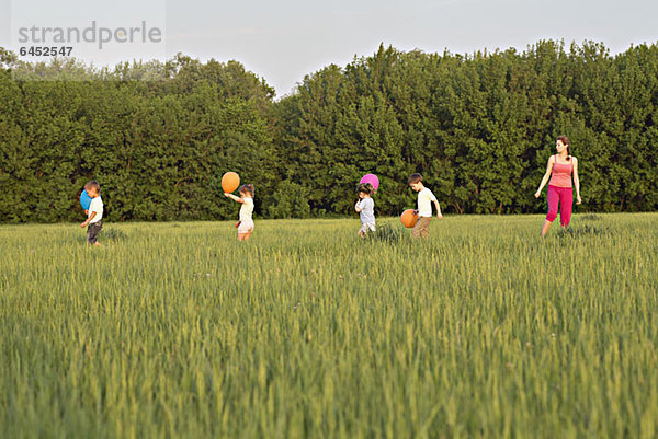 Eine Frau steht auf einem Feld mit vier Kindern.