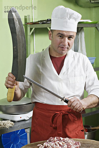 Ein Koch beim Schärfen eines großen Messers