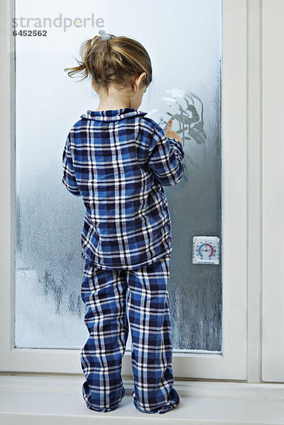 Ein Mädchen im Pyjama und mit Kondensation auf Glas.
