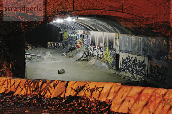 Skateboard-Rampen und Graffiti im Tunnel bei Nacht