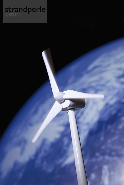 Ein Modell einer Windkraftanlage vor dem Planeten Erde