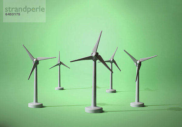 Fünf Modelle von Windkraftanlagen auf grünem Grund