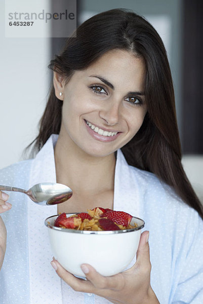 Frau mit Frühstücksschale mit Müsli und Erdbeeren