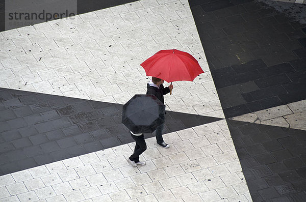 Zwei Fußgänger mit Regenschirmen