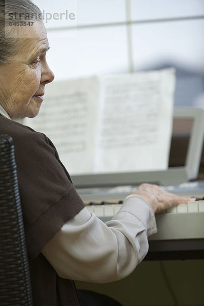 Eine ältere Frau sitzt am Klavier.