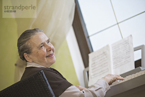 Eine fröhliche Seniorin am Klavier