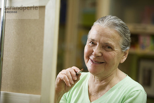 Eine fröhliche Seniorenfrau mit einem Pinsel