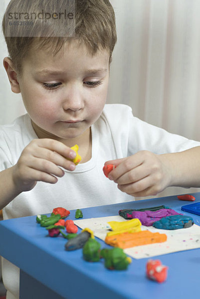 Ein kleiner Junge spielt mit verschiedenfarbigem Kinderspielzeug.
