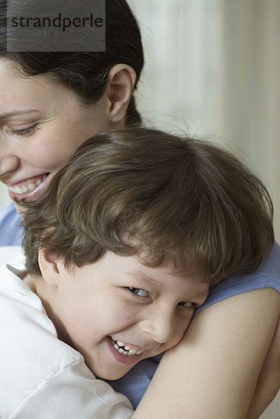 Eine Mutter und ihr kleiner Sohn umarmen und lachend