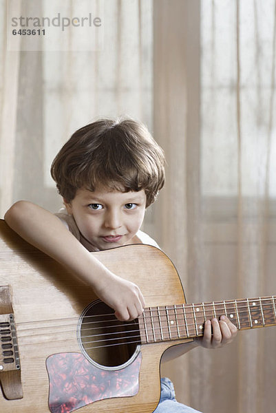 Ein kleiner Junge hält eine Akustikgitarre.