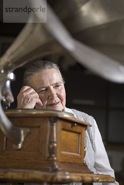 Eine ältere Frau  die ein Grammophon hört.