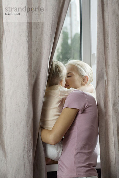 Eine liebevolle Mutter und Tochter am Fenster