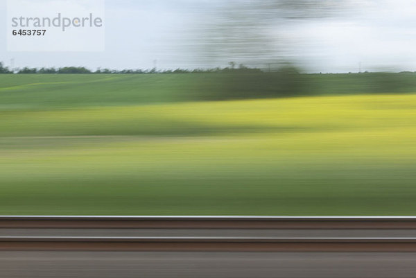 Eine ländliche Landschaft in verschwommener Bewegung vom fahrenden Zug aus gesehen