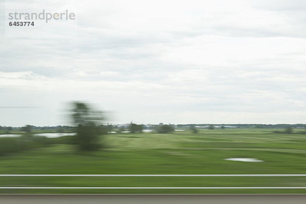 Eine ländliche Landschaft in verschwommener Bewegung vom fahrenden Zug aus gesehen