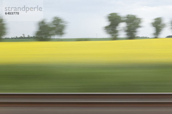 Eine ländliche Landschaft in verschwommener Bewegung vom fahrenden Zug aus gesehen