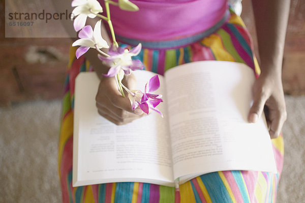 niedrig  Anschnitt  sitzend  Frau  Buch  Stuhl  Blume  halten  Taschenbuch  vorlesen