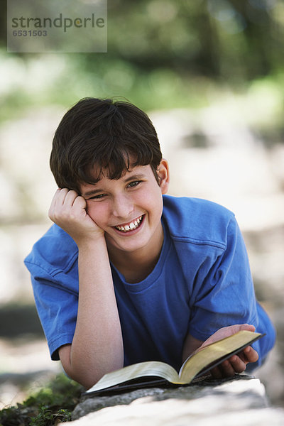 Außenaufnahme  Buch  lächeln  Junge - Person  Taschenbuch  freie Natur