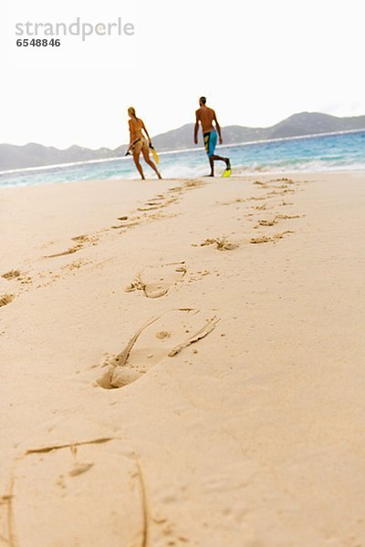 Diving flipper prints on sand  mid adult couple in background