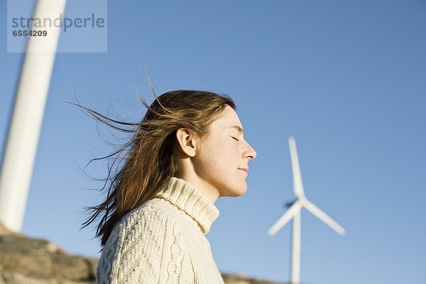 Profile of young woman  wind turbines in background