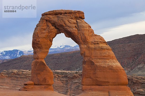 Eroded natural arch  snowcapped mountains in background