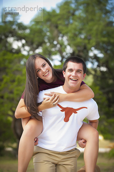 USA  Texas  Teenager Junge gibt Huckepack an Teenager Mädchen  lächelnd  Portrait