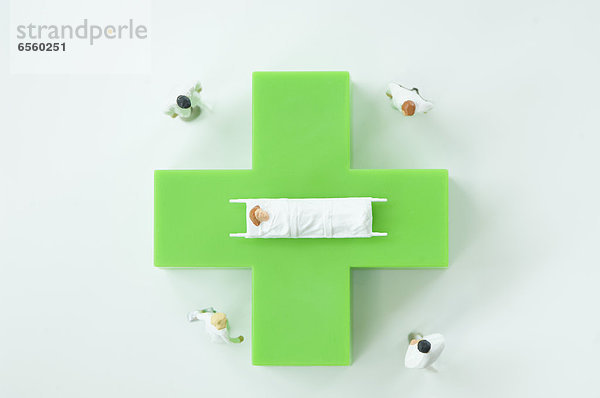 Figuren von Ärzten und Patienten mit grünem medizinischen Symbol