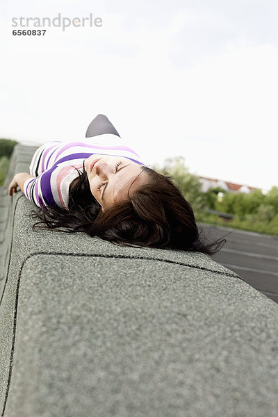 Young woman lying on wall