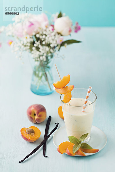 Vanille und Pfirsich Smoothie mit Blumenstrauß auf dem Tisch  Nahaufnahme