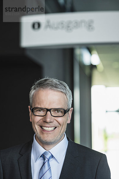 Germany  Stuttgart  Businessman standing in office building  portrait  smiling