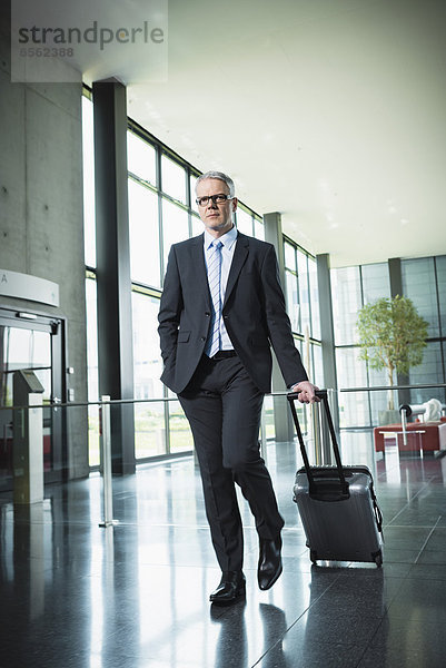 Germany  Stuttgart  Businessman pulling luggage in office building