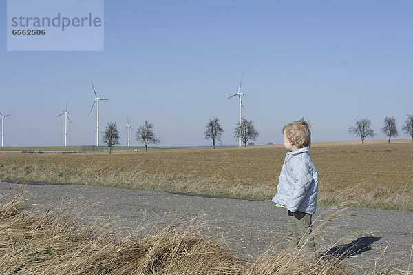 Junge steht auf der Straße  Windkraftanlage im Hintergrund