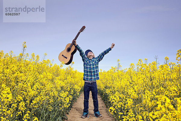 Junge im Feld stehend mit Akustikgitarre