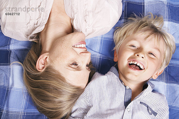 Germany  Cologne  Mother and son lying on blanket  smiling