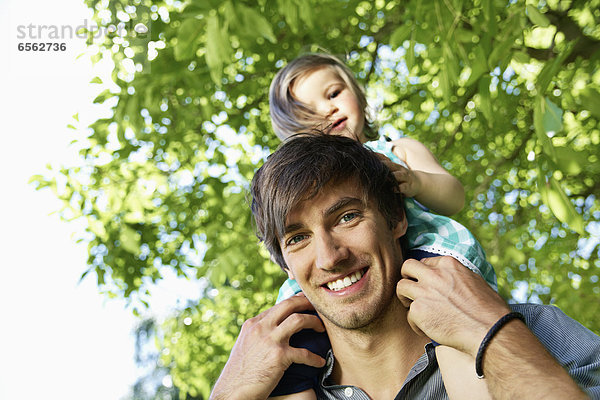 Germany  Cologne  Father carrying daughter on shoulders  smiling