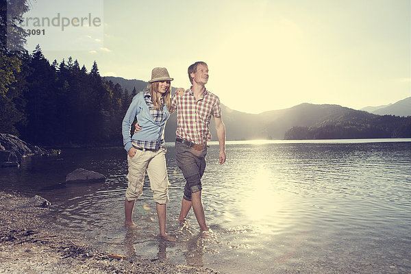 Deutschland  Bayern  Paar im Wasser laufen  lächelnd